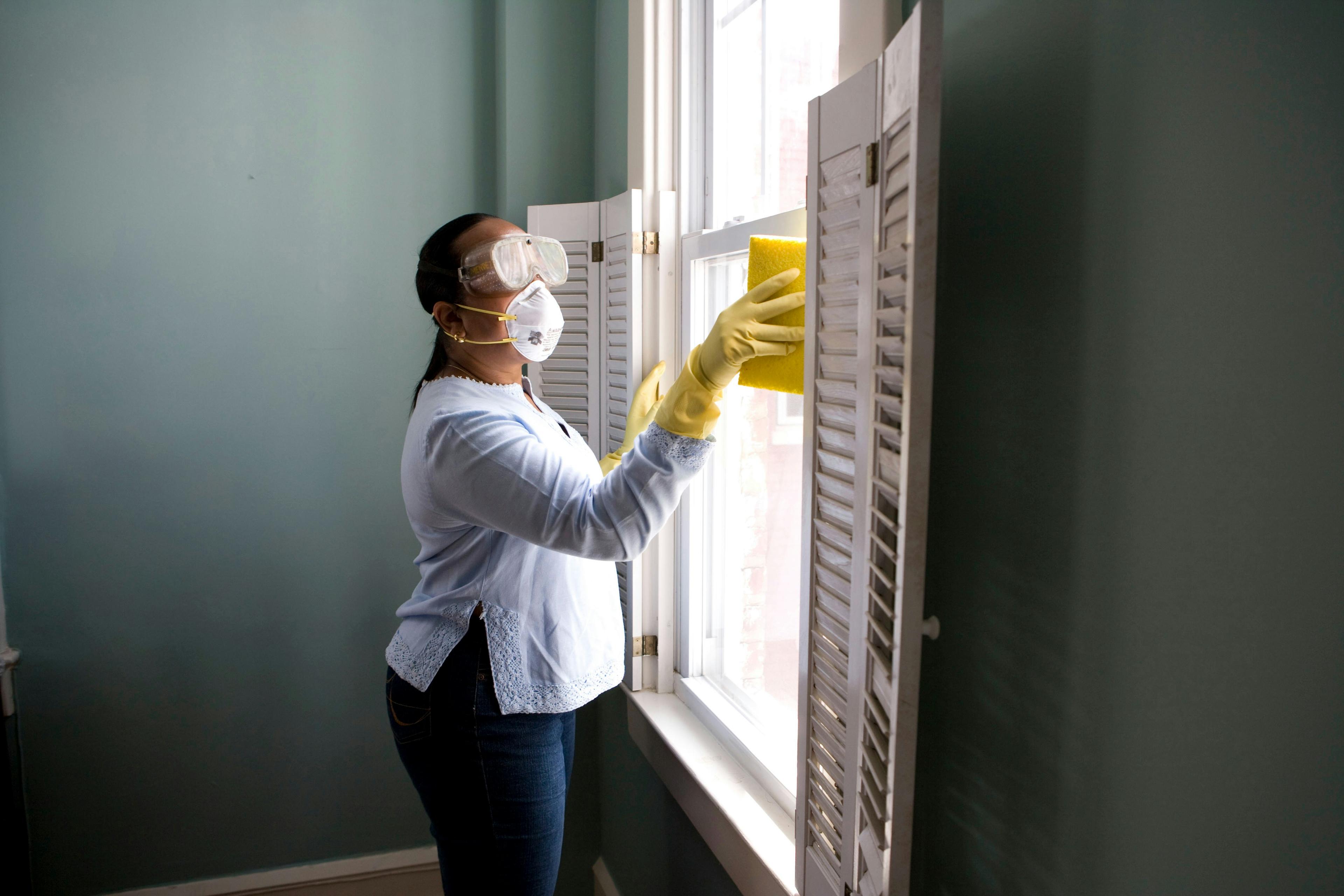Cleaner wiping down windows in a bright corporate space